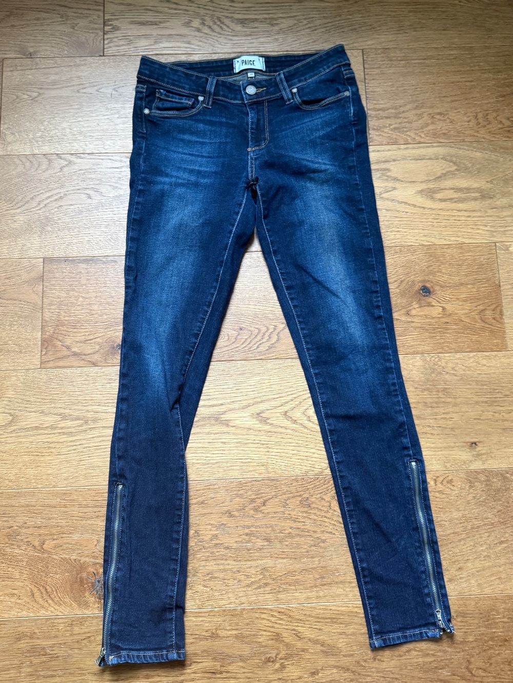 Paige dark wash skinny jeans and functional ankle zipper details.